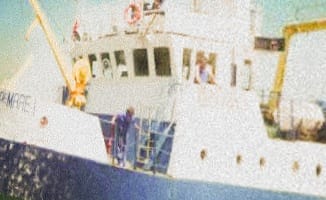 The cropped challenge photo: a partial name board on the bow, blue hull, white superstructure, blue external stairway